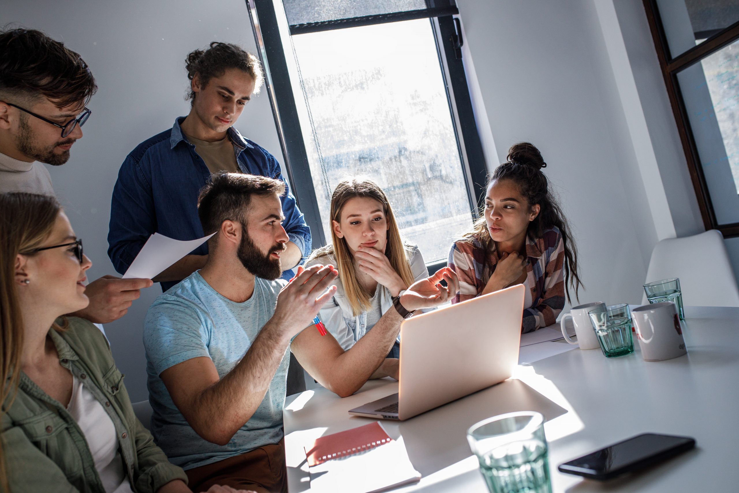 Junge Menschen beim Versicherungsvergleich Junge Menschen sitzend am Bürotisch. Sie vergleichen die Berufsunfähigkeitsversicherung.
